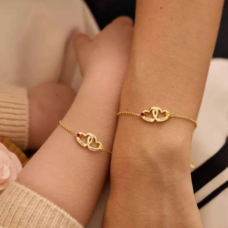 Two personalized gold heart bracelets worn on a couple's wrists