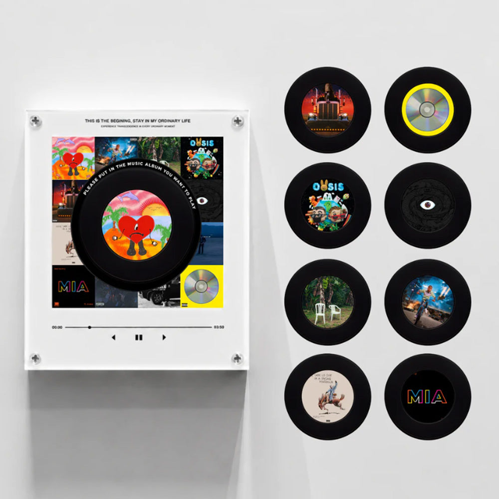 A wall-mounted music display featuring a white console with a large vinyl record and a grid of nine smaller vinyl records on a light gray wall. The album art and record designs are colorful and varied, with the word 'MIA' visible on several records.