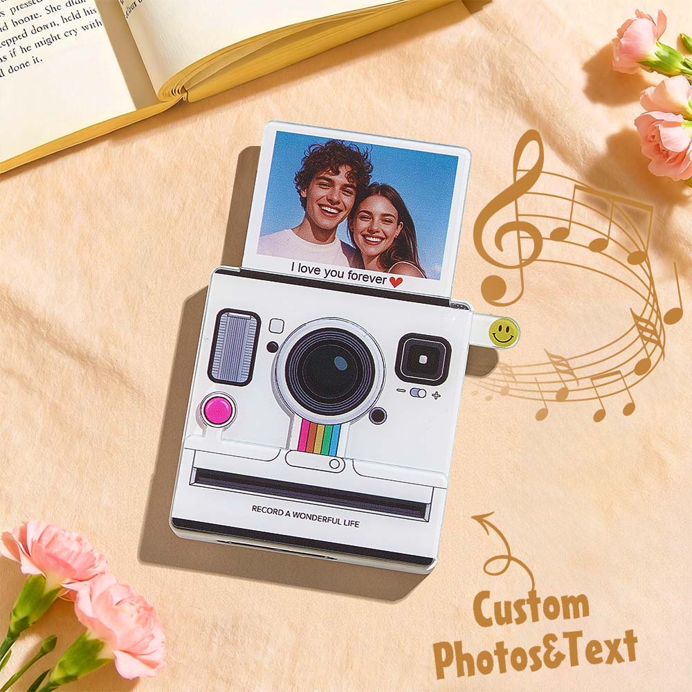 Camera-shaped product with a photo of a couple and 'I love you forever' text on a light wooden surface with flowers and music notes.