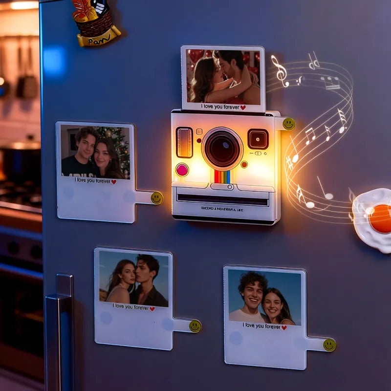 Decorative refrigerator magnet shaped like a camera with photos and music notes on a metallic surface.